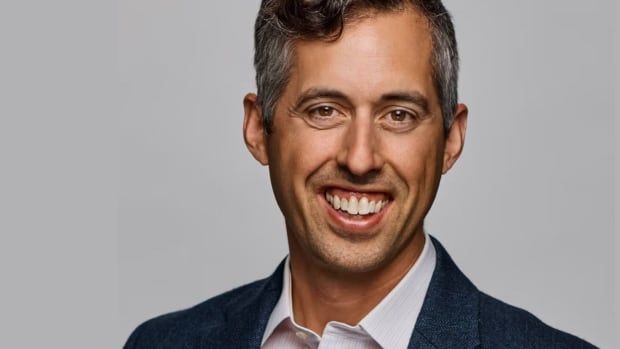 A man in a suit smiles for a photo.