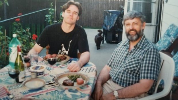 An old photo of two men sitting at a dinner table. 