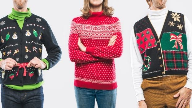 A panoramic image of a large group of people wearing knit ugly Christmas sweaters and cardigans with various bizarre patterns and decorations.  Horizontal on white studio background.