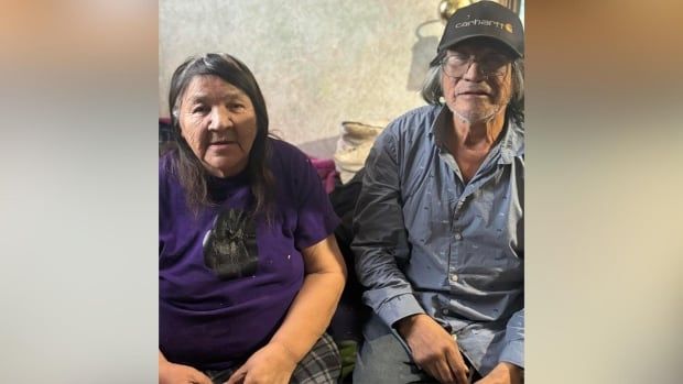 Older couple stare into the camera sitting on a bed in a camping trailer