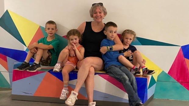 An older woman sits on blocks with four young kids.