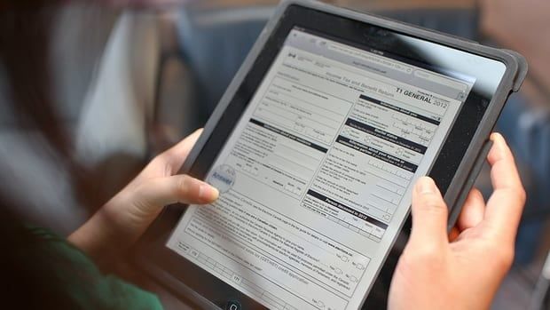 A person holds a tablet that displays an online income tax form.