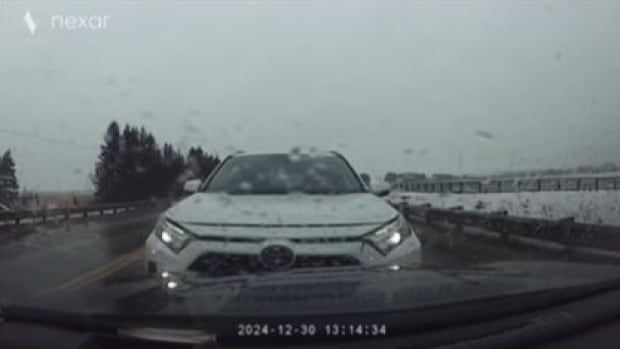 A screenshot from dashcam shows a white SUV driving towards a car on a highway.