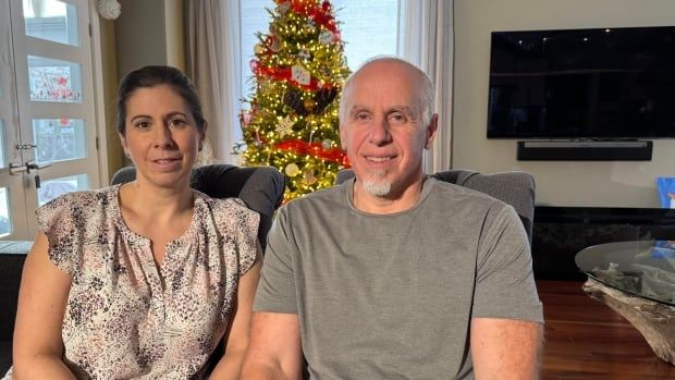 A husband and wife sitting smiling in their living room. 