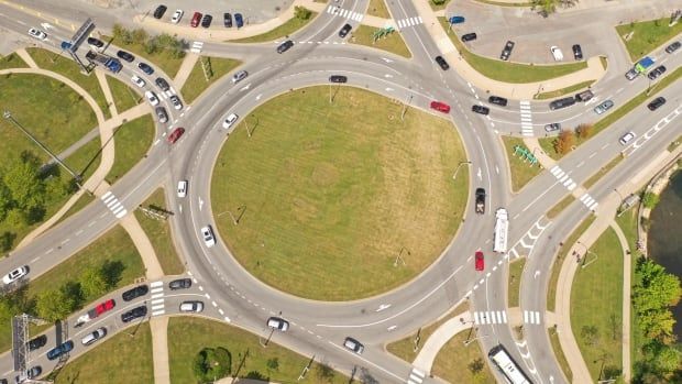 Top-down view of cars going through a roundabout during the day.