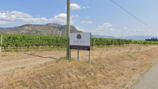 A sign that reads Desert Hills Estate in front of a vineyard.