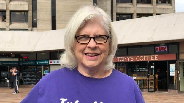 A woman wearing a purple tshirt and glasses smiles