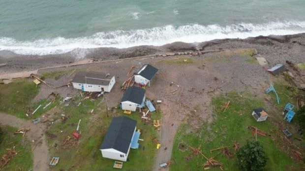 An aerial view of the damage done to Glenghorm Beach Resort. Debris is scattered around four cottages with an unsettled ocean nearby.