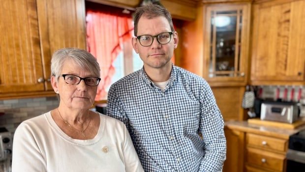 Betty Waite and her son Todd stand in the kitchen of her home in Sherbrooke, staring seriously at the camera. 