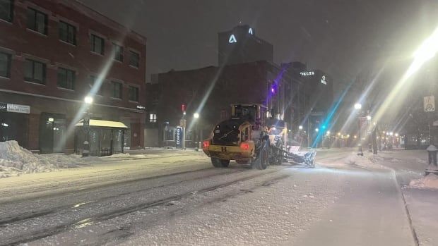 A snow plow going down a covered street. 