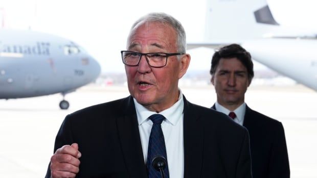 Prime Minister Justin Trudeau stands behind National Defence Minister Bill Blair as they hold a press conference on Canada's new defence policy at CFB Trenton in Trenton, Ont. on Monday, April 8, 2024.