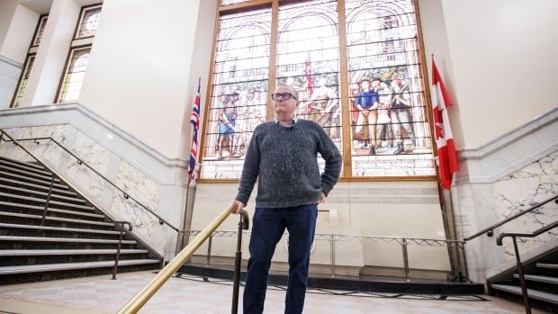 Historian Michael McClelland is pictured in front of an original stained glass window in the soon-to-be-vacant Old City Hall building, in Toronto, on Jan. 23, 2025.