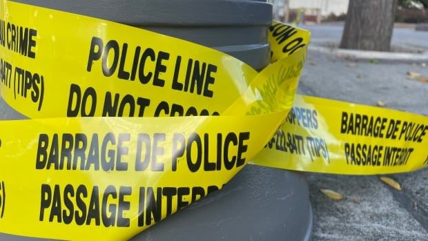 Yellow police tape wrapped around a sidewalk pole.