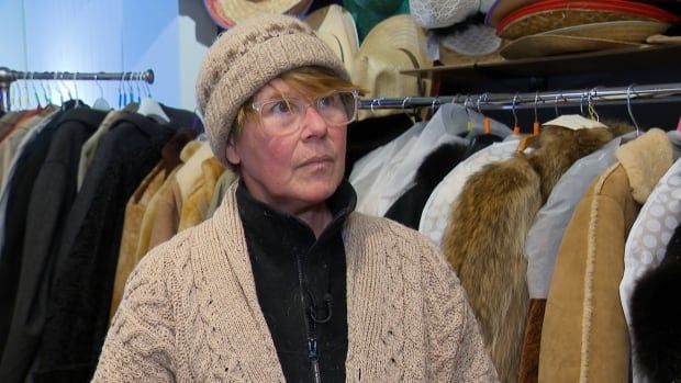 A woman in a knit hat stands in a clothing store