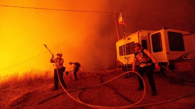 Firefighters hold a hose as they battle a wildfire