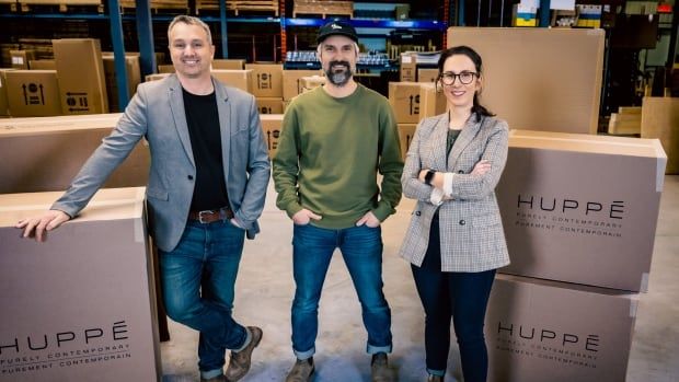 Three people pose inside a warehouse