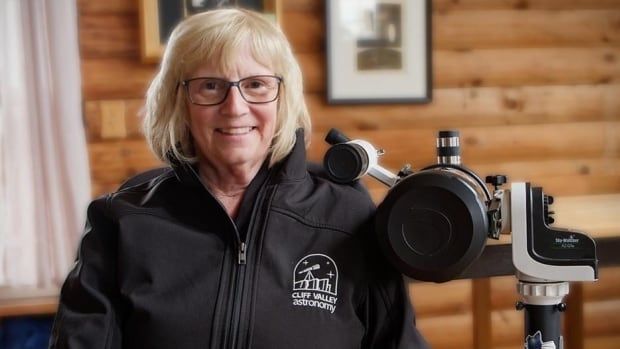 Woman stands next to photography equipment. 