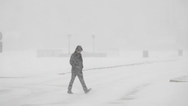 A person walks  through a blizzard