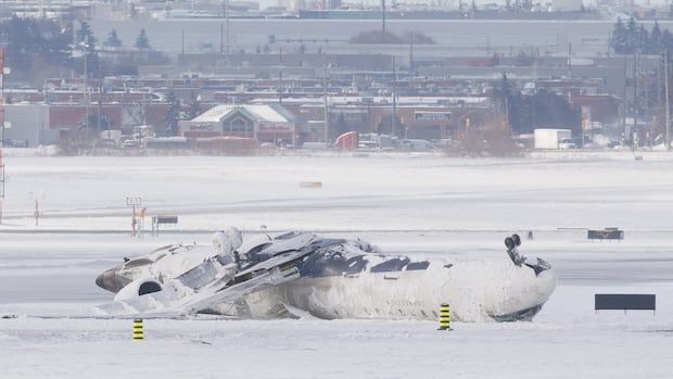 The wreckage of a Delta Air Lines operated CRJ900 aircraft lies on the runway following a crash at Toronto Pearson International Airport