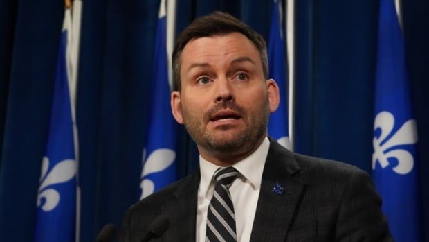 A closeup of PQ leader Paul St-Pierre Plamondon's face in front of a Quebec flag backdrop at the National Assembly.