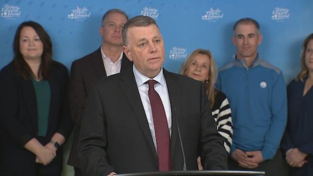 Man stands at podium with family members standing behind him