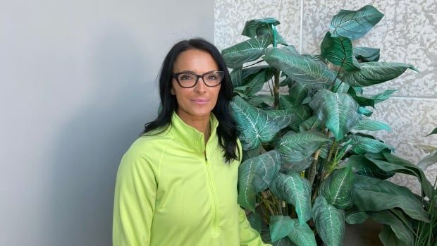 Denise Treleaven stands next to plant.