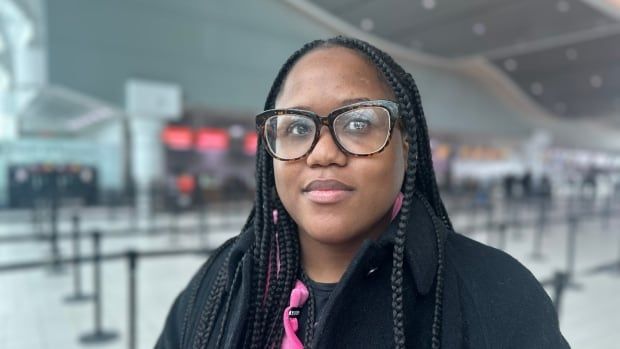 A woman stands in an airport looking annoyed