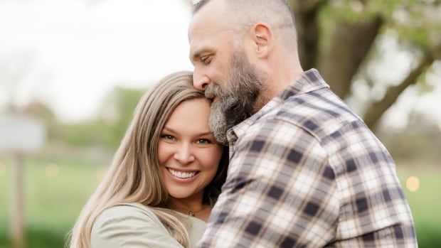 Two people smiling and hugging outdoors.