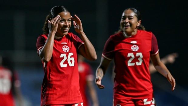 A female soccer player celebrates with her teammate.