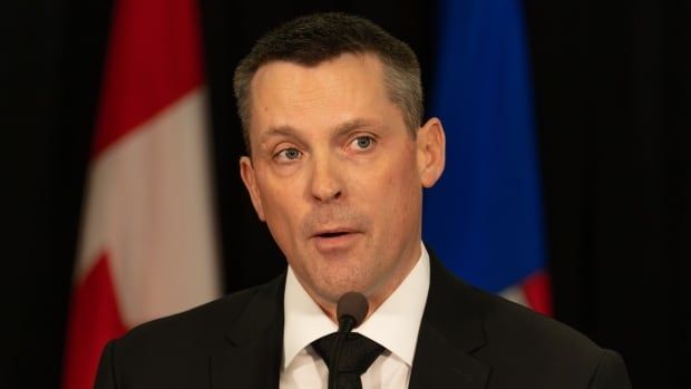 Close-up of a man standing in front of two flags. 