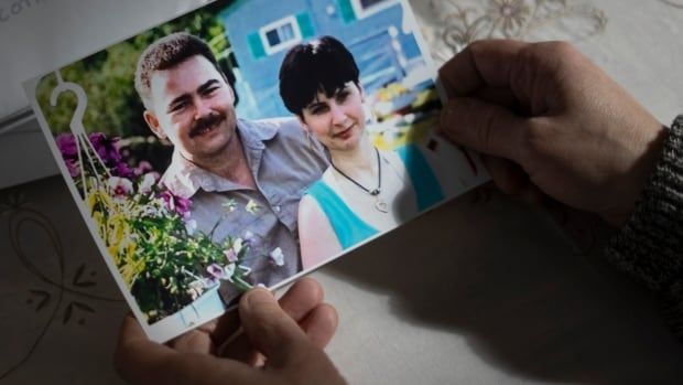 A photo of a man and a woman are held in a woman's hands.