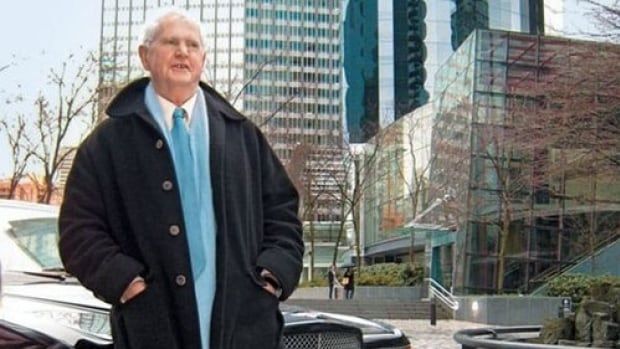 An older man stands in front of skyscrapers. 