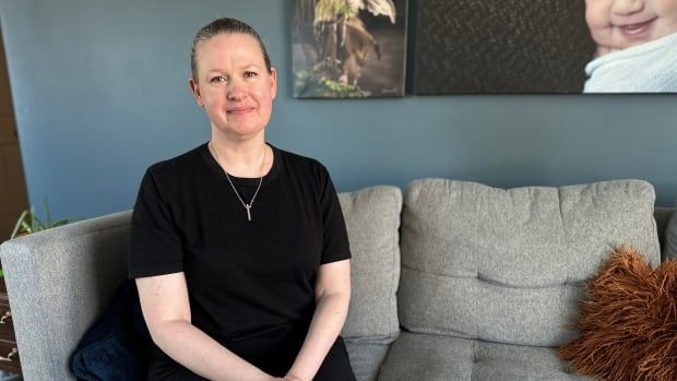 Woman smiles into camera while sitting on couch