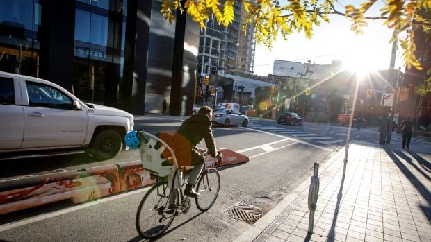 A man rides in the bike lane at golden hour as the sun beams down on him. 