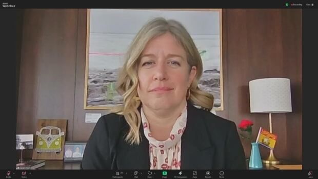  Woman with blond hair sits at desk with a slight smile on her face.