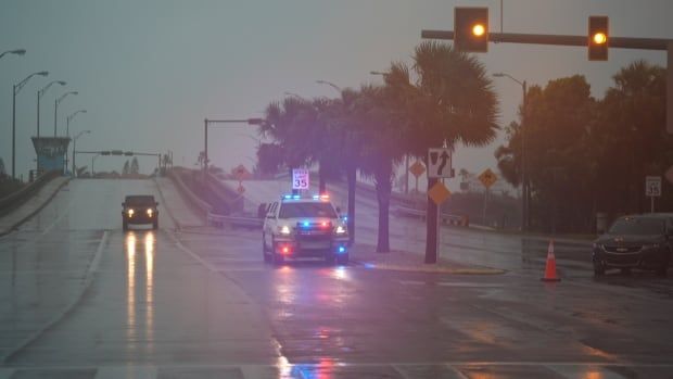 Two vehicles are shown on a roadway with their lights on, in a semi-darkened sky.