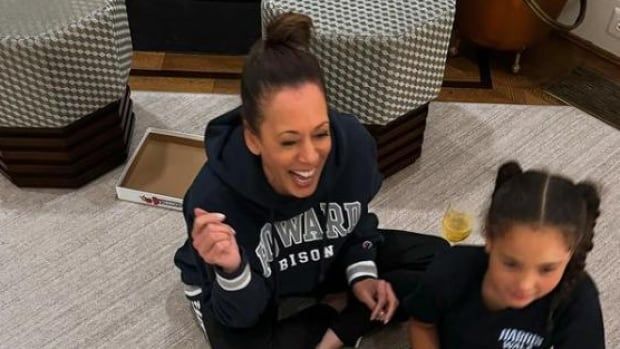 A woman sits on the floor laughing with two young children