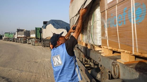 A man with a blue UN vests checks truck.