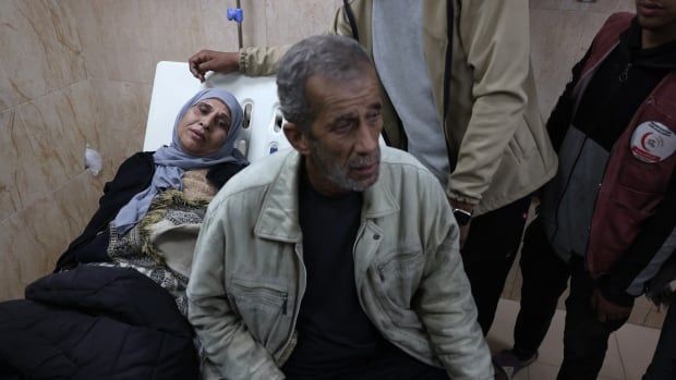 A woman lies down on a stretcher with a man sitting next to her.