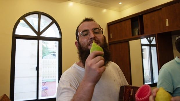 A person is photographed holding up a piece of fruit.