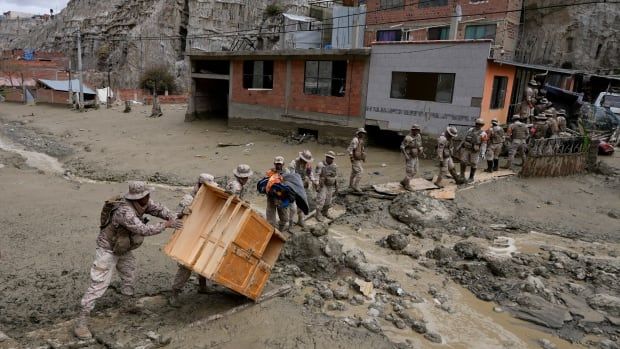 Soldiers form a line as they move furniture across a road devastated by a mud slide.