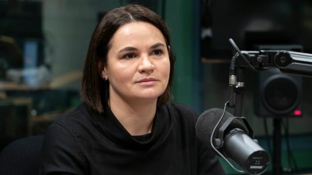 A woman with a short brown bob sits in front of a microphone