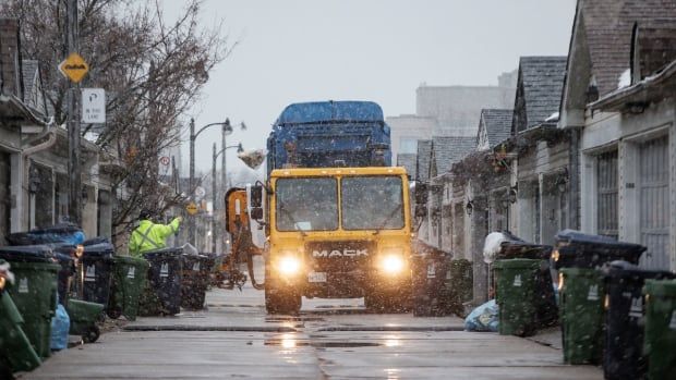 A worker tosses recycling into a recycling truck.