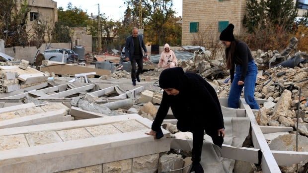 People inspect site of damaged building and rubble.