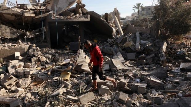 A man inspects rubble of a house