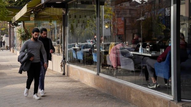 People walk past a cafe.