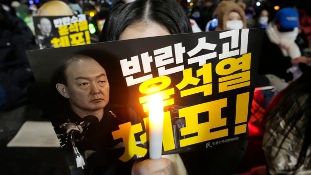 A protester holds up a sign urging the "arrest" of the "rebellion leader" Yoon Suk Yeol, the president of South Korea.