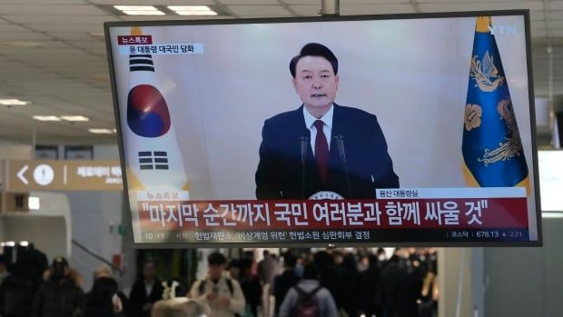 A TV screen shows South Korean President Yoon Suk Yeol delivering a statement.