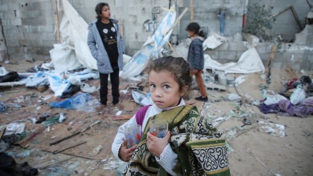 A girl stands  amid rubble