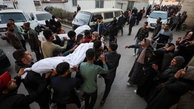 People carry a white body bag.